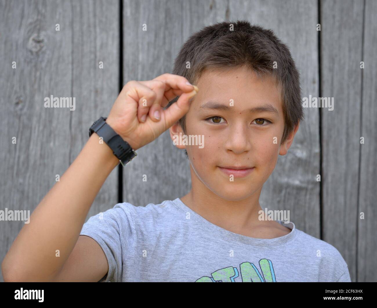 Mixed-race Pre-teen boy (Ostasiatisch und Kaukasisch) zeigt mit seiner rechten Hand das chinesische Handzeichen für die Nummer 7 (Fotoserie: Bild-Nr. 7 von 10). Stockfoto