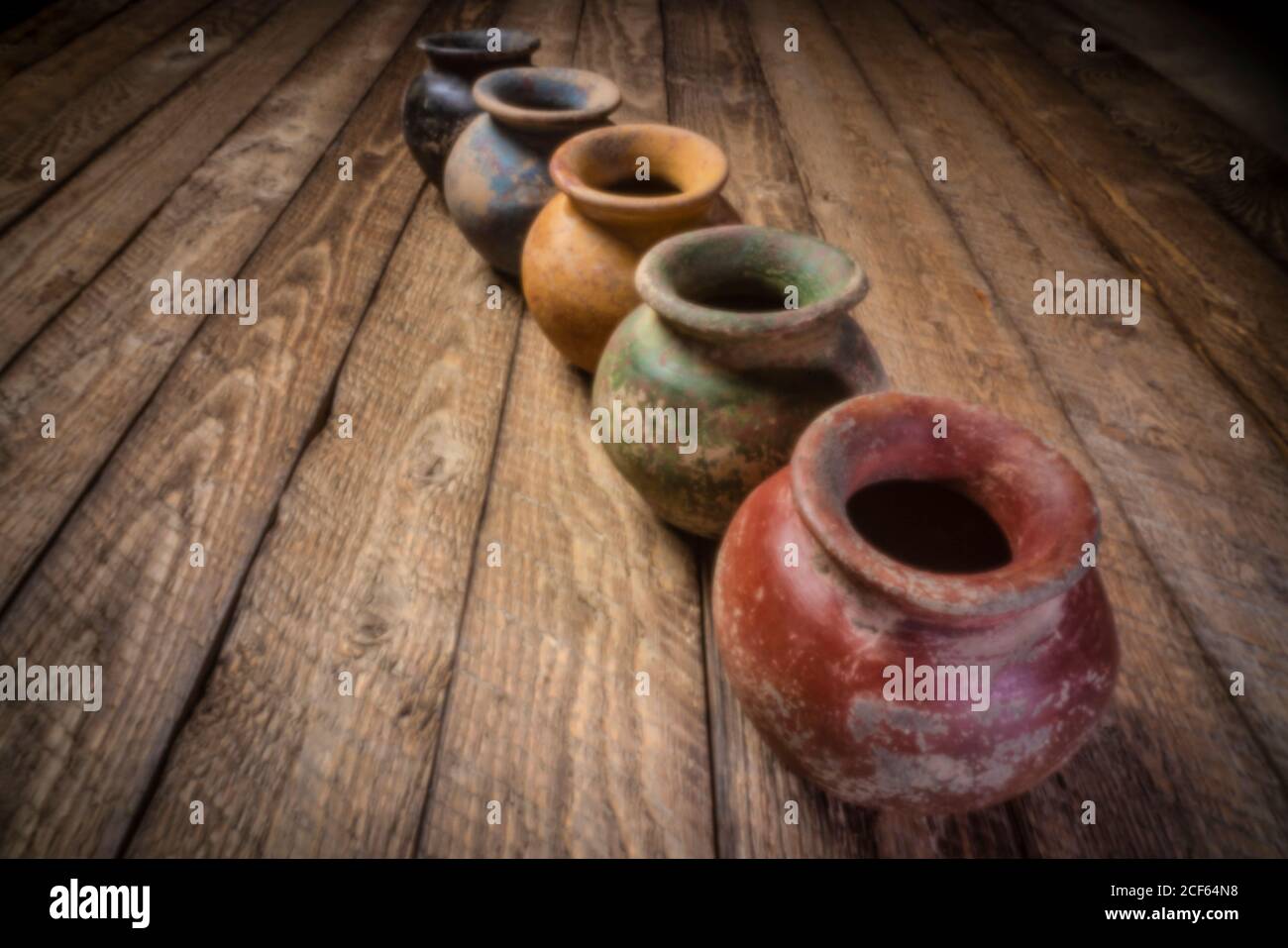 Row os kleine Grunge Tontöpfe mit rauer Farbgebung auf einem verwitterten Holz, Weichfokus-Bild mit lenless Lochkamera aufgenommen Stockfoto