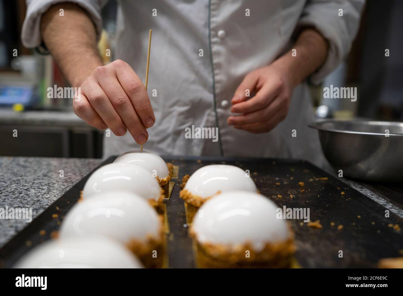 Crop Person setzen einen Holzstab in Kuchen auf angeordnet Metallbrett in der Küche Stockfoto