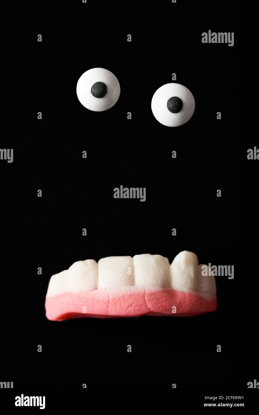 Lustige Kreatur, halloween Monster, Zuckeraugen und Gummizähne auf schwarzem Hintergrund Stockfoto