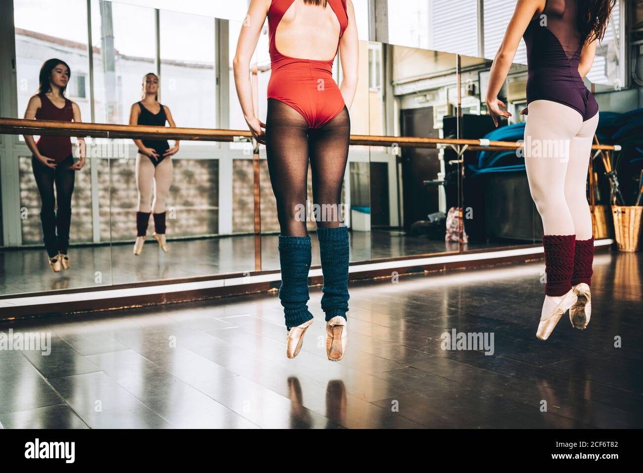 Crop Frauen in Bodysuits springen auf pointe über dem Boden in Studio-Training Ballett. Stockfoto