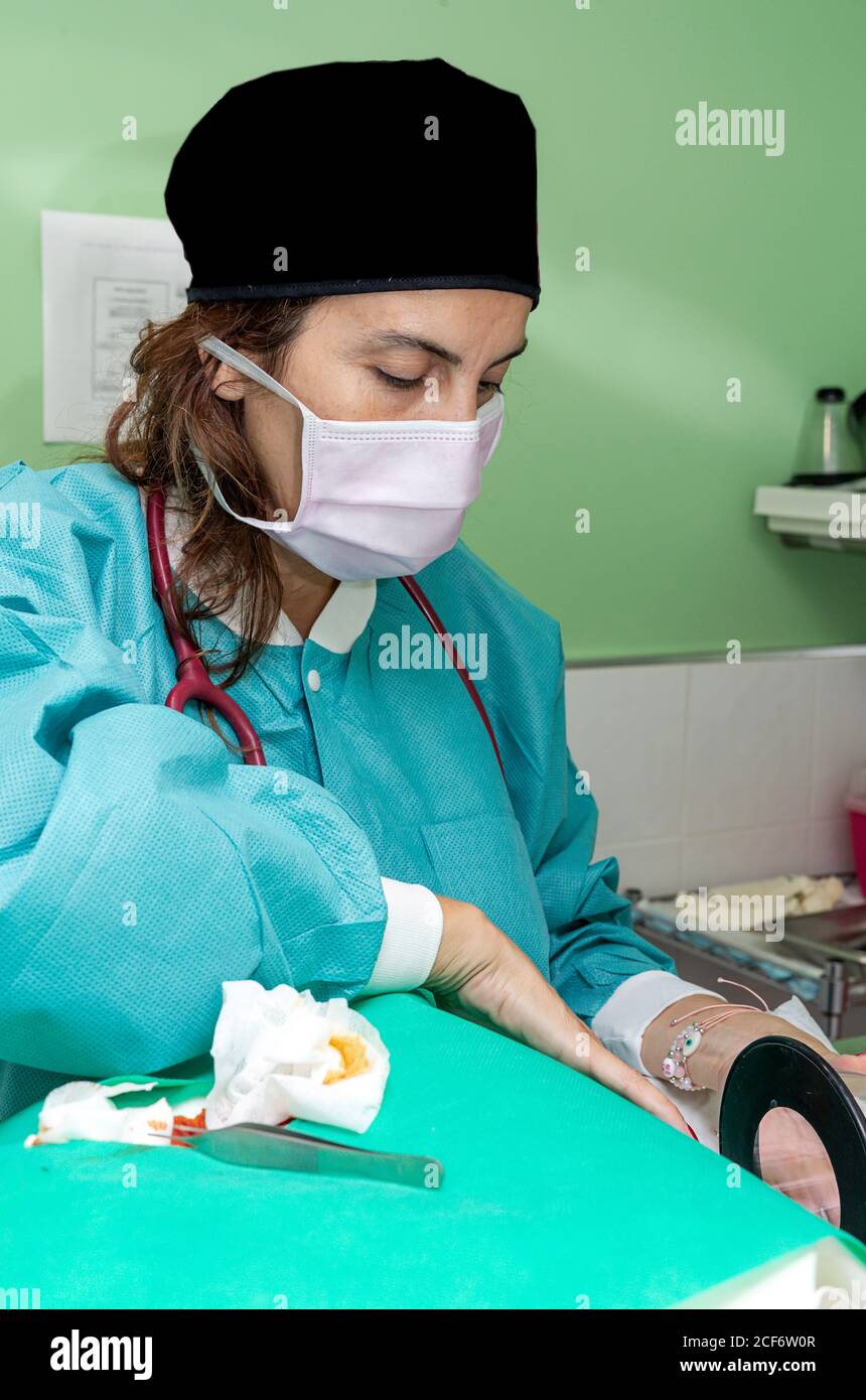 Fröhlicher Sanitäter in grüner Uniform mit Schere stehen und machen Chirurgie in der Klinik Stockfoto