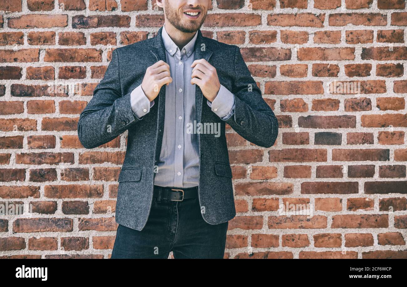 Anzug Mann smart casual Outfit junge Geschäftsmann Anpassung Kragen seines blauen Wolle Blazer mit Hemd gegen Backstein Wand Hintergrund im Büro. Stadt Stockfoto