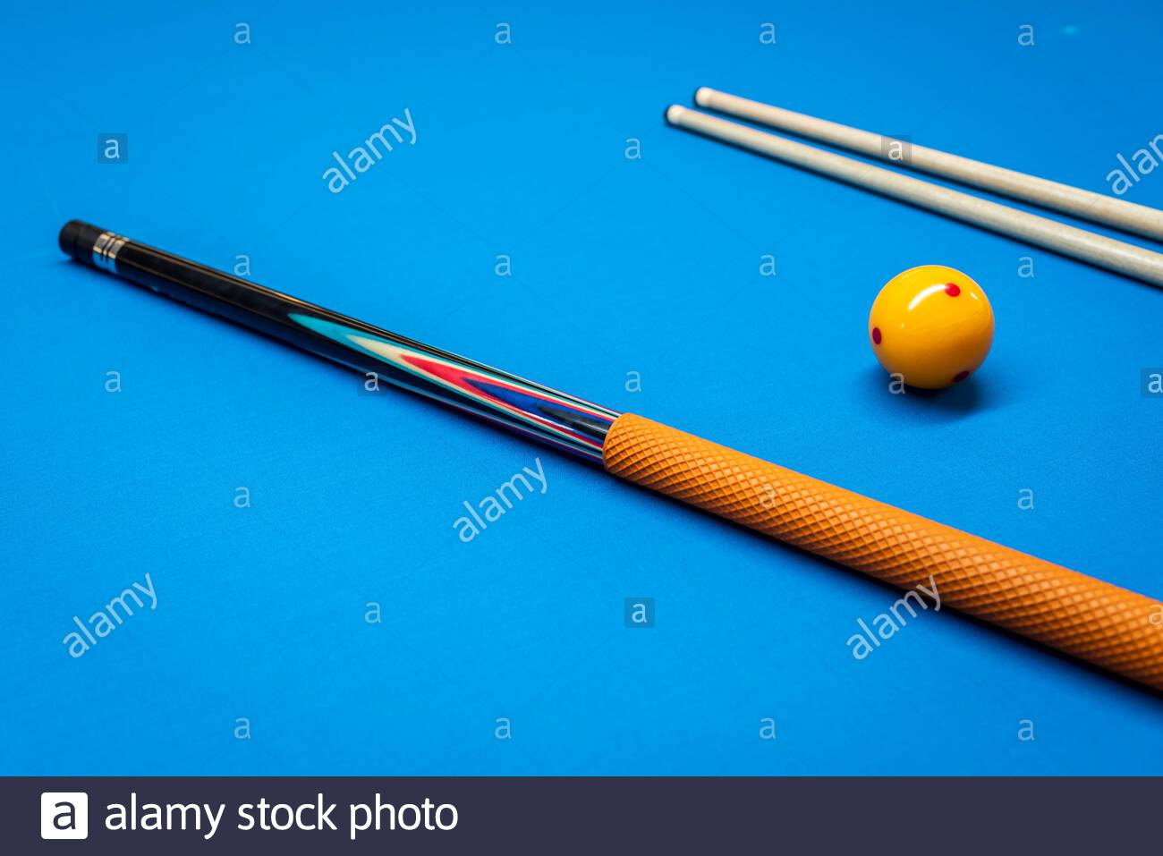 Queuesticks und eine gelbe Kugel auf einem Billardtisch. Stockfoto