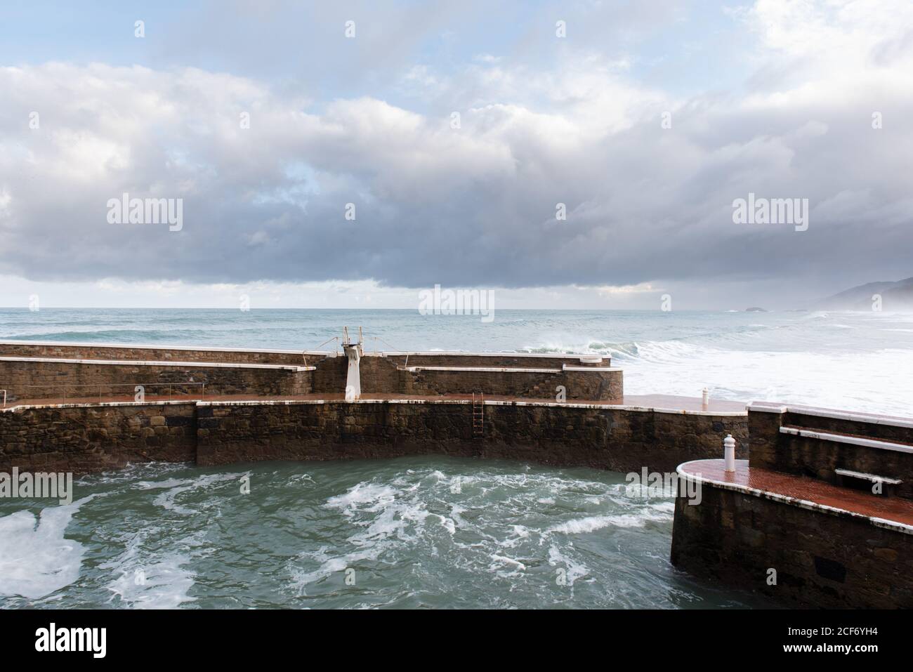 Landschaft von eingezäunt mit Steinmauern Wasser und wellig blau Meer mit bewölktem Himmel auf dem Hintergrund bei Zarautz bei Spanien Stockfoto