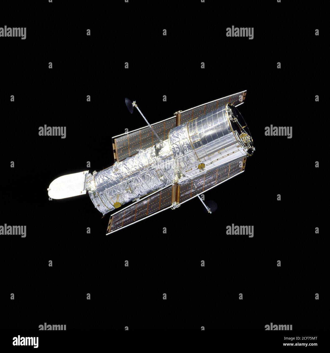 Orbiter Discovery führt nach der Wiederauslösung auf der zweiten Wartungsmission HST SM-02 einen Flyaround des Hubble Space Telescope (HST) durch. Das silberne Teleskop, mit geöffneter Öffnung, wird scharf von der samtigen Schwärze des Weltraums kontrastiert. Stockfoto