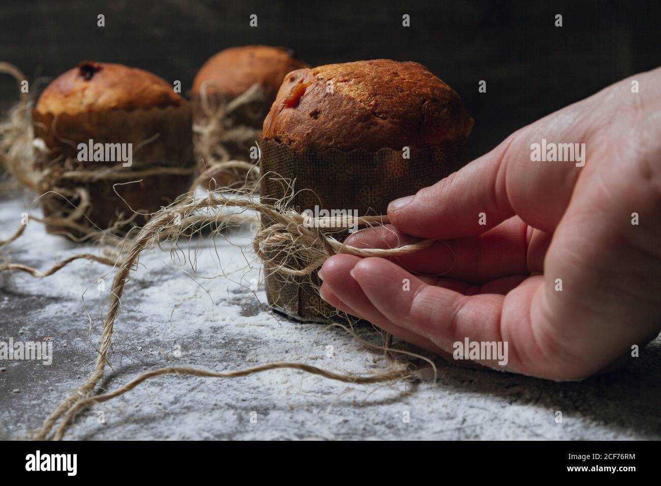 Crop Person Arrangieren Garn auf frisch gebackenen hausgemachten Weihnachtskuchen Auf Tisch mit weißem Mehl gepudert Stockfoto