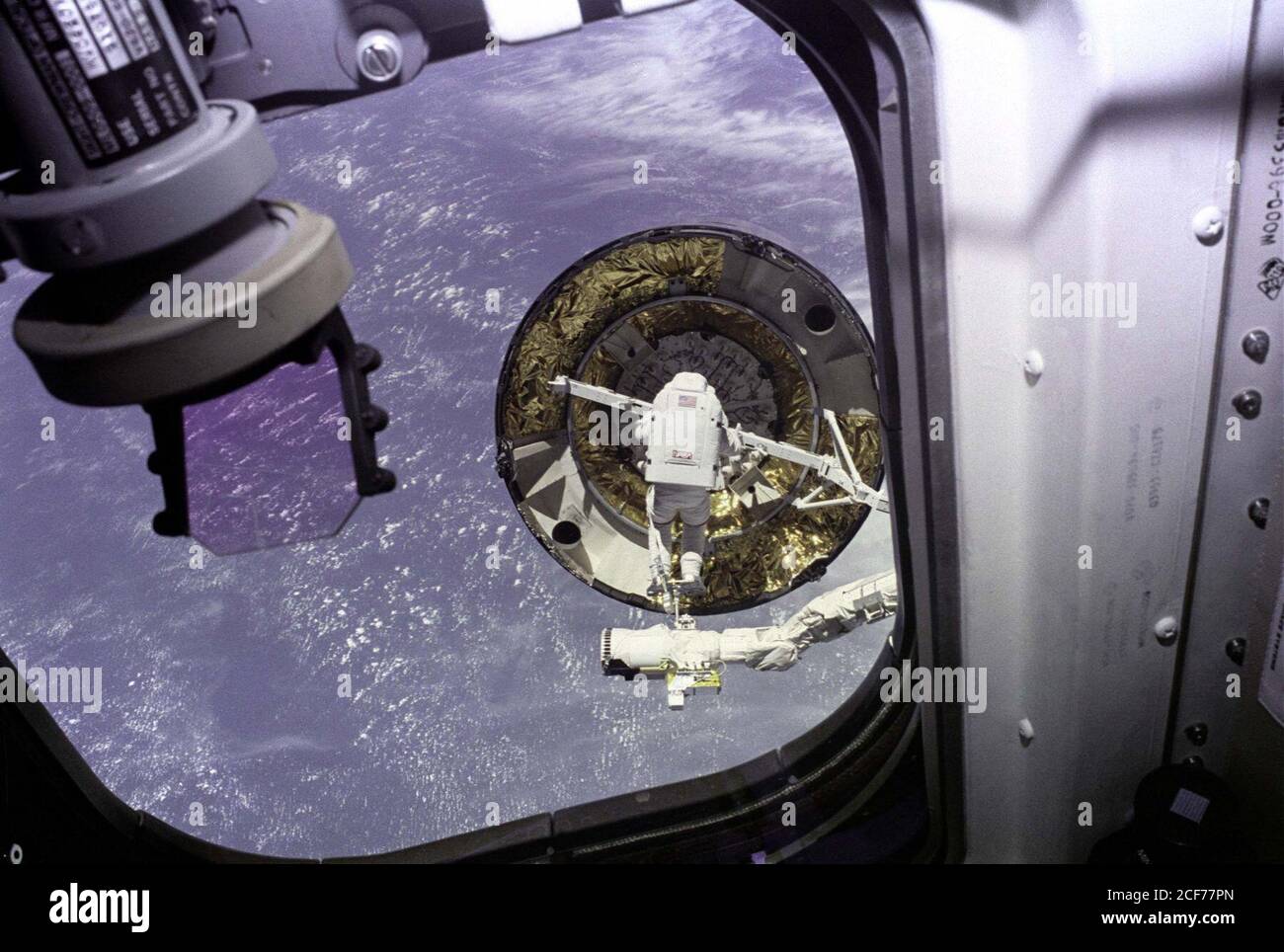 Der erste einzelne Besatzungsmitglied EVA-Capture-Versuch der Intelsat VI aus der Endeavour Achterdeck Fenster gesehen. EVA Mission Specialist Pierre Thuot steht auf der Endeffektor-Plattform des Remote-Manipulatorsystems (RMS), wobei die Satellitenerfassungsleiste versucht, sie an den frei schwebenden Kommunikationssatelliten anzuschließen. Stockfoto