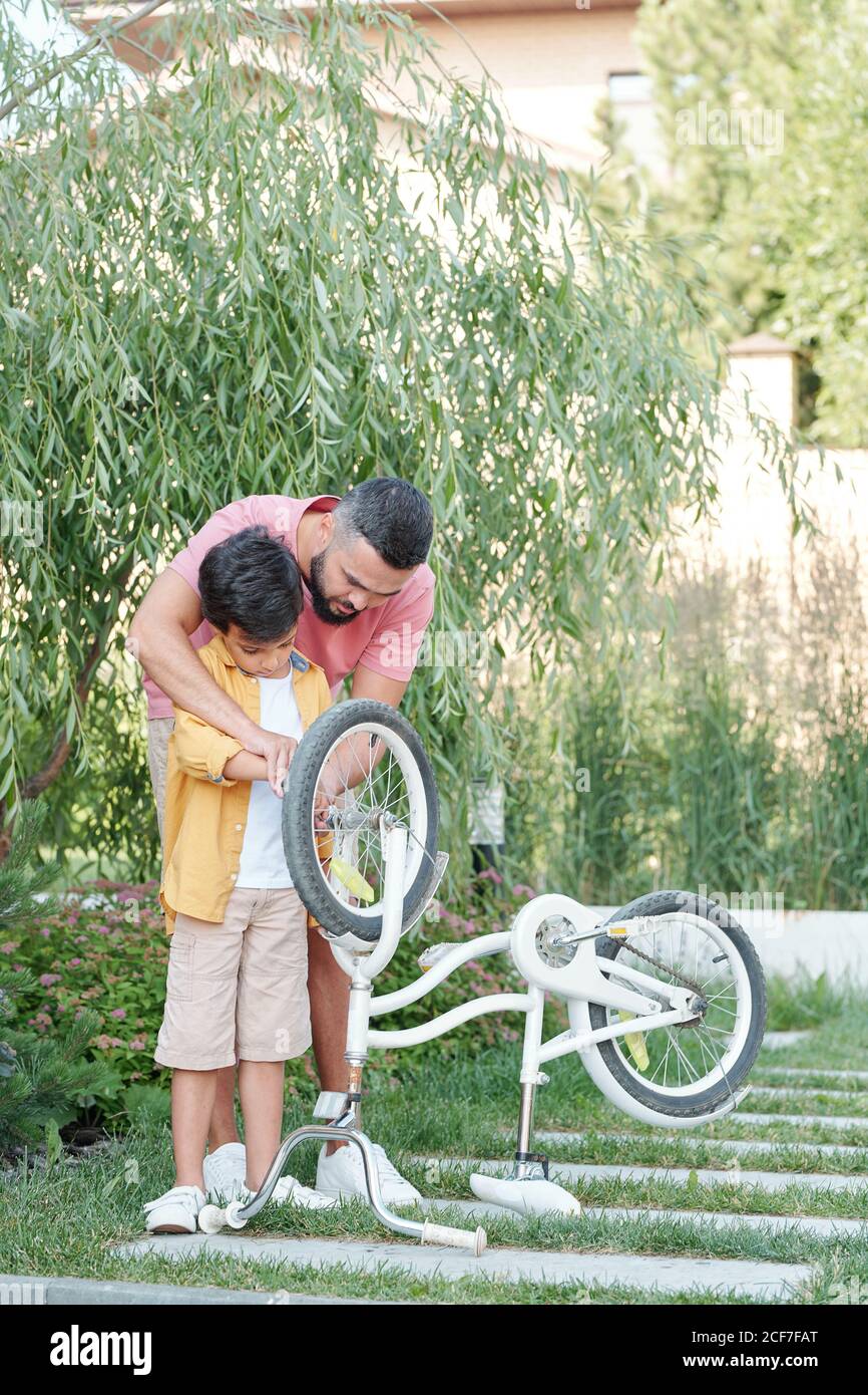 Liebevoller Vater und sein Sohn verbringen Zeit zusammen im Freien Reparatur Fahrrad an sonnigen Tag, vertikale Aufnahme, Kopierraum Stockfoto