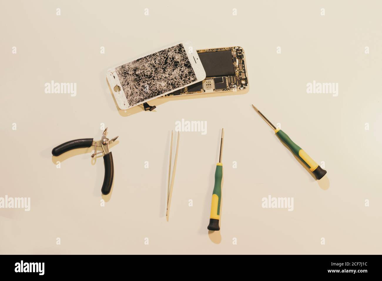 Verschiedene Reparatur-Ausrüstung auf weißem Hintergrund in der Nähe von modernen Smartphone platziert Mit beschädigtem Bildschirm Stockfoto