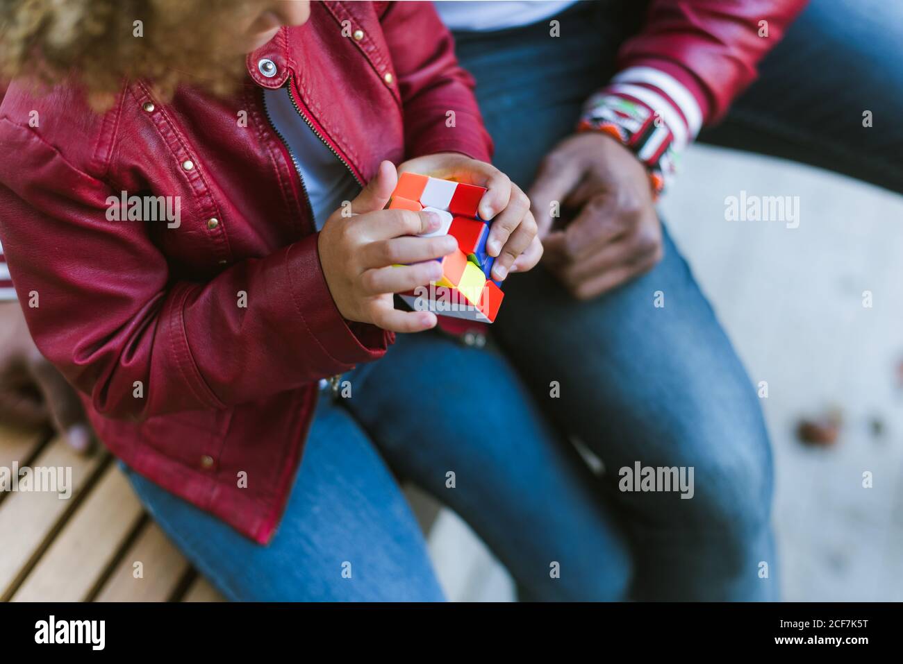Verkrümmter Vater mit Tochter in ähnlichem Outfit sitzend Treppen und rubik Cube spielen, während Sie Tag zusammen in verbringen Stadt Stockfoto