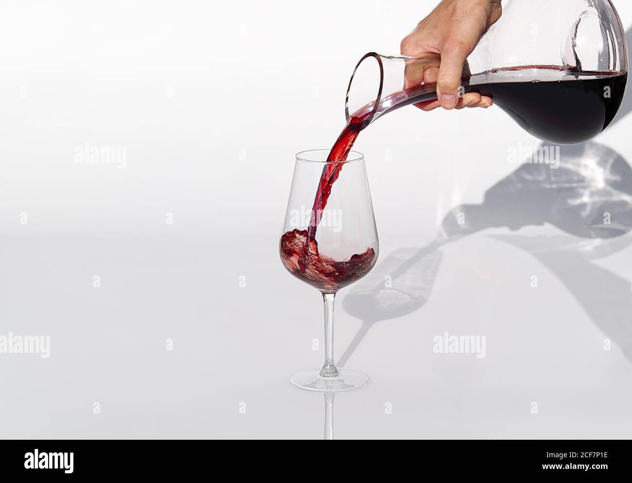 Sommelier gießt Rotwein von Dekanter bis Weinglas auf weißen Hintergrund. Stockfoto