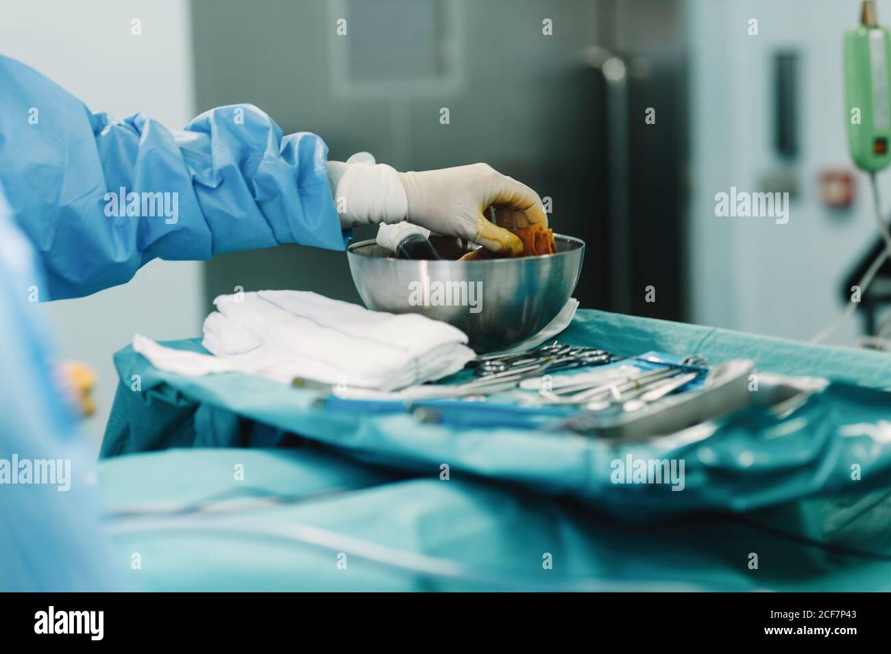 Crop Hand von Sanitäter in blauem Kleid und weißen Handschuh Tampon mit Jod  in der Schale während der Operation zusammendrücken Stockfotografie - Alamy