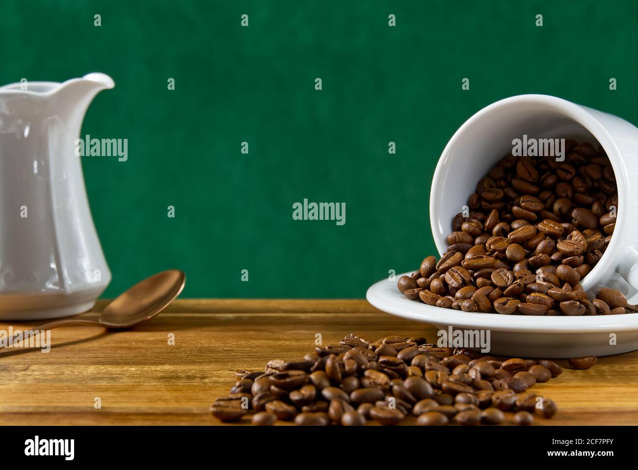 Internationaler Tag des Kaffees Konzept. Nahaufnahme weiße Kaffeetasse voller Kaffeebohnen auf dunkelgrünem Hintergrund. Stockfoto