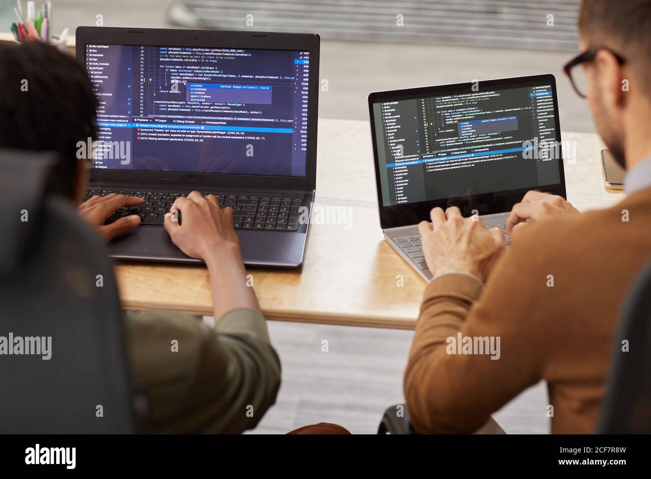 Rückansicht von zwei Grafikern, die am Tisch sitzen Und tippen auf ihren Computern entwickeln sie neue Software Stockfoto