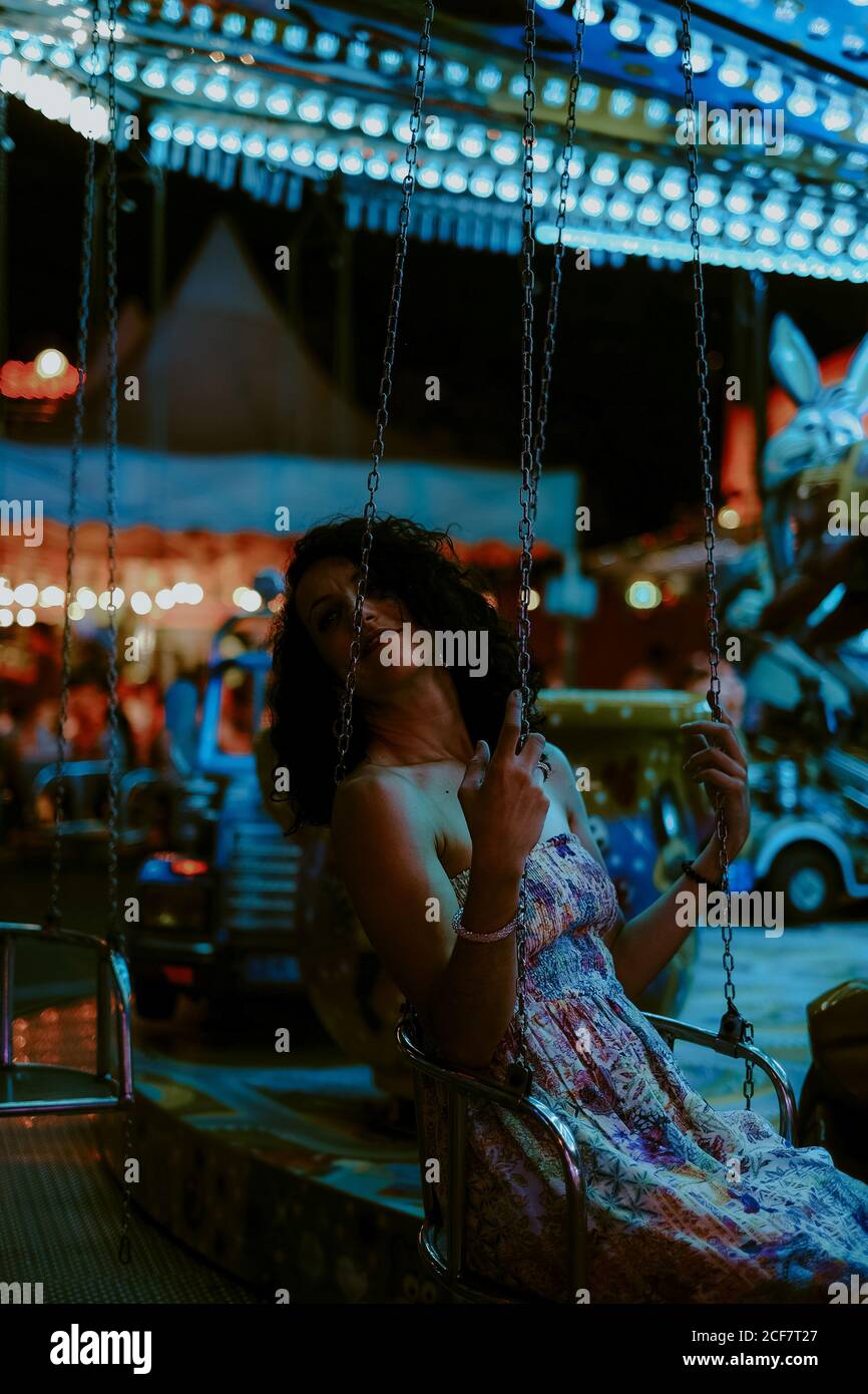 Schöne Frau genießen Fahrt auf Karussell auf dem Jahrmarkt während Sommerabend auf verschwommenem Hintergrund Stockfoto