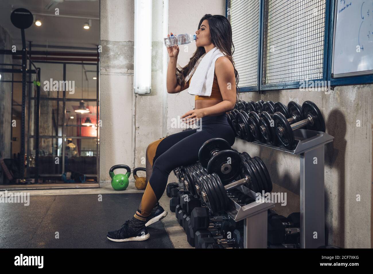 Junge Sportlerin trinkt Wasser im Fitnessstudio Stockfoto