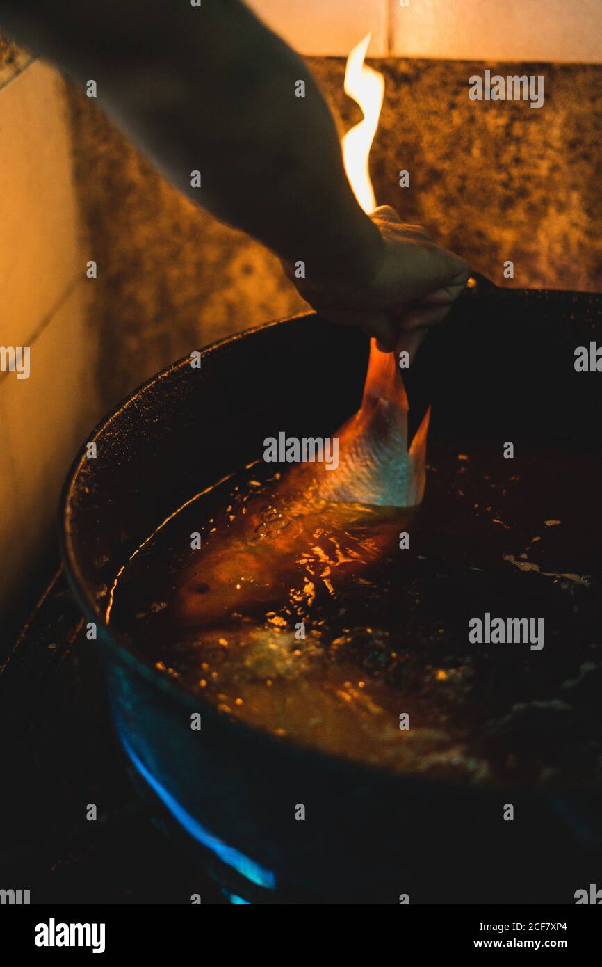 Von oben faceless Kochen Braten frischen Fisch in großer Pfanne Mit Öl in rustikaler Küche Stockfoto