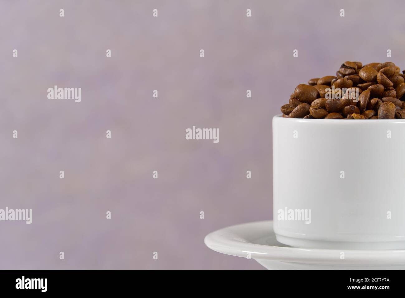 Internationaler Tag des Kaffees Konzept. Nahaufnahme weiße Kaffeetasse voller Kaffeebohnen auf alten Rosen Hintergrund. Stockfoto