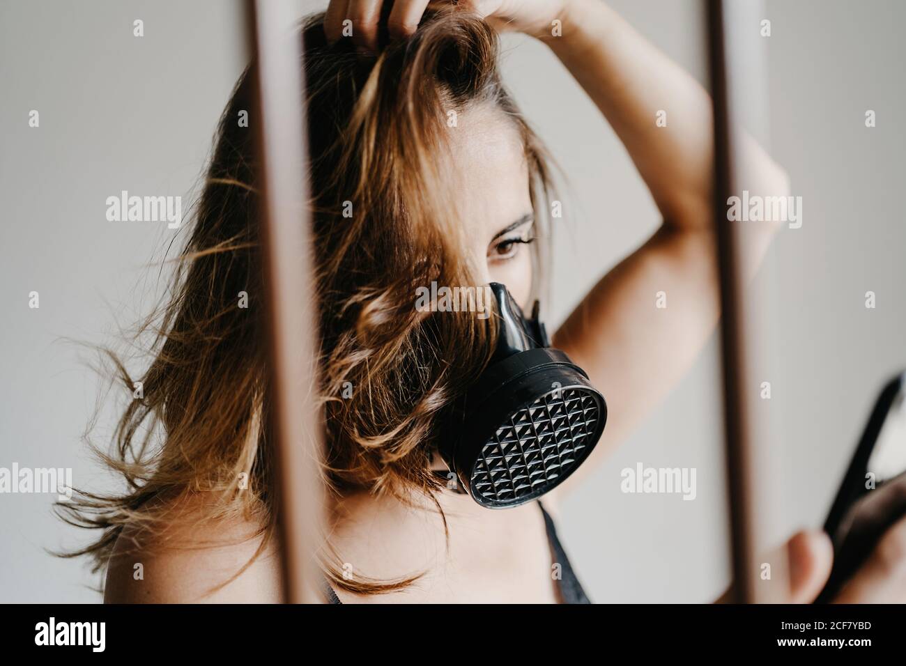 Junge Frau in schwarzer Atemschutzmaske für Coronavirus Prävention stehen Hinter Gittern und im Handy surfen Stockfoto