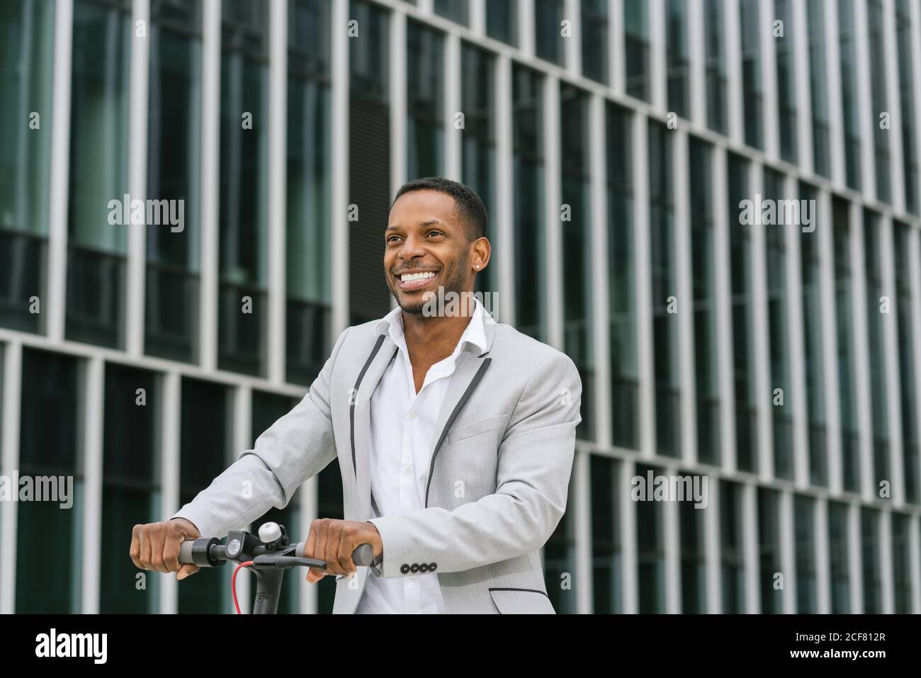 Schwarzer Mann im Anzug auf Elektroroller im Business Center Stockfoto
