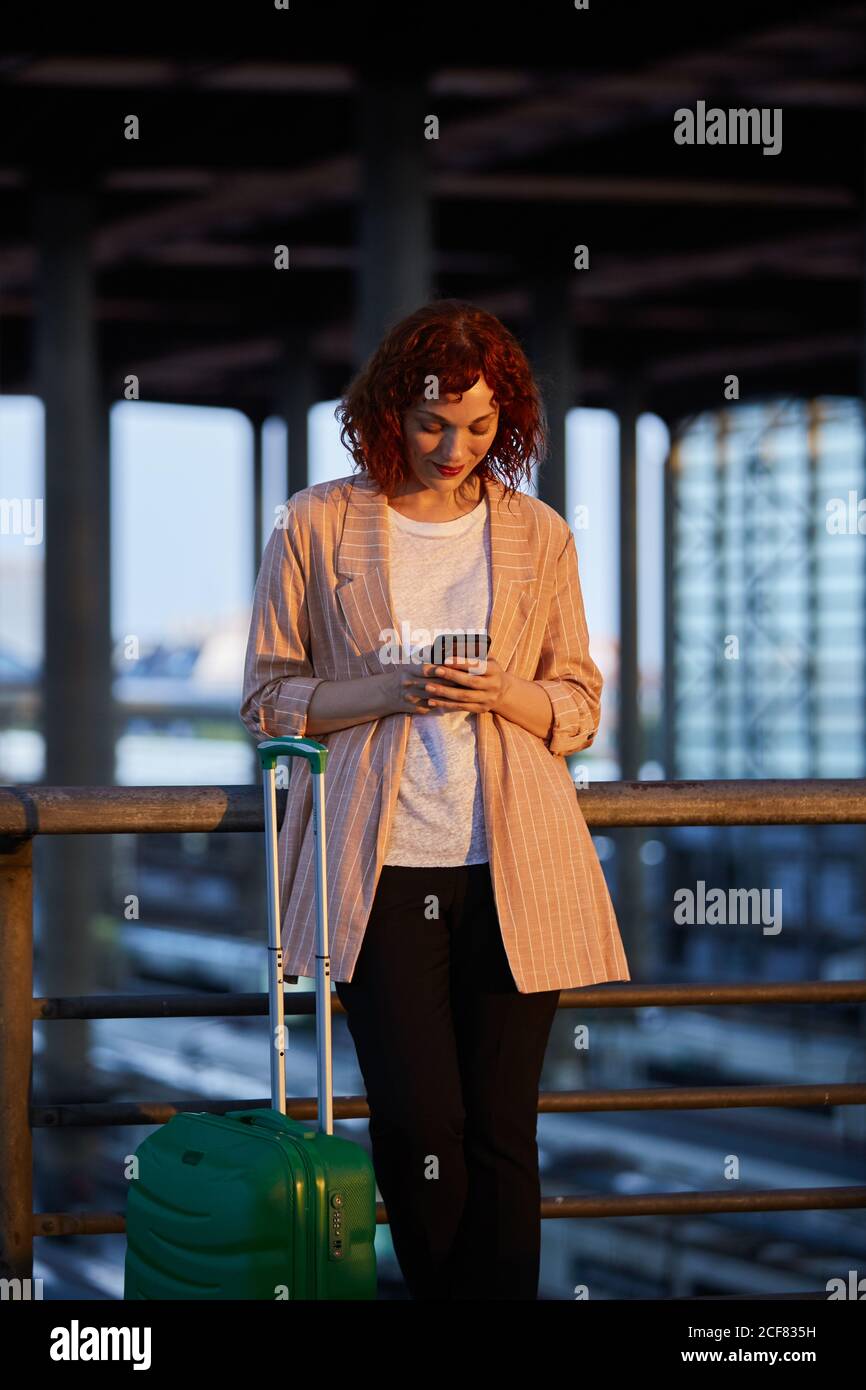 Lächelnde junge Frau, die am Bahnhof telefoniert Stockfoto