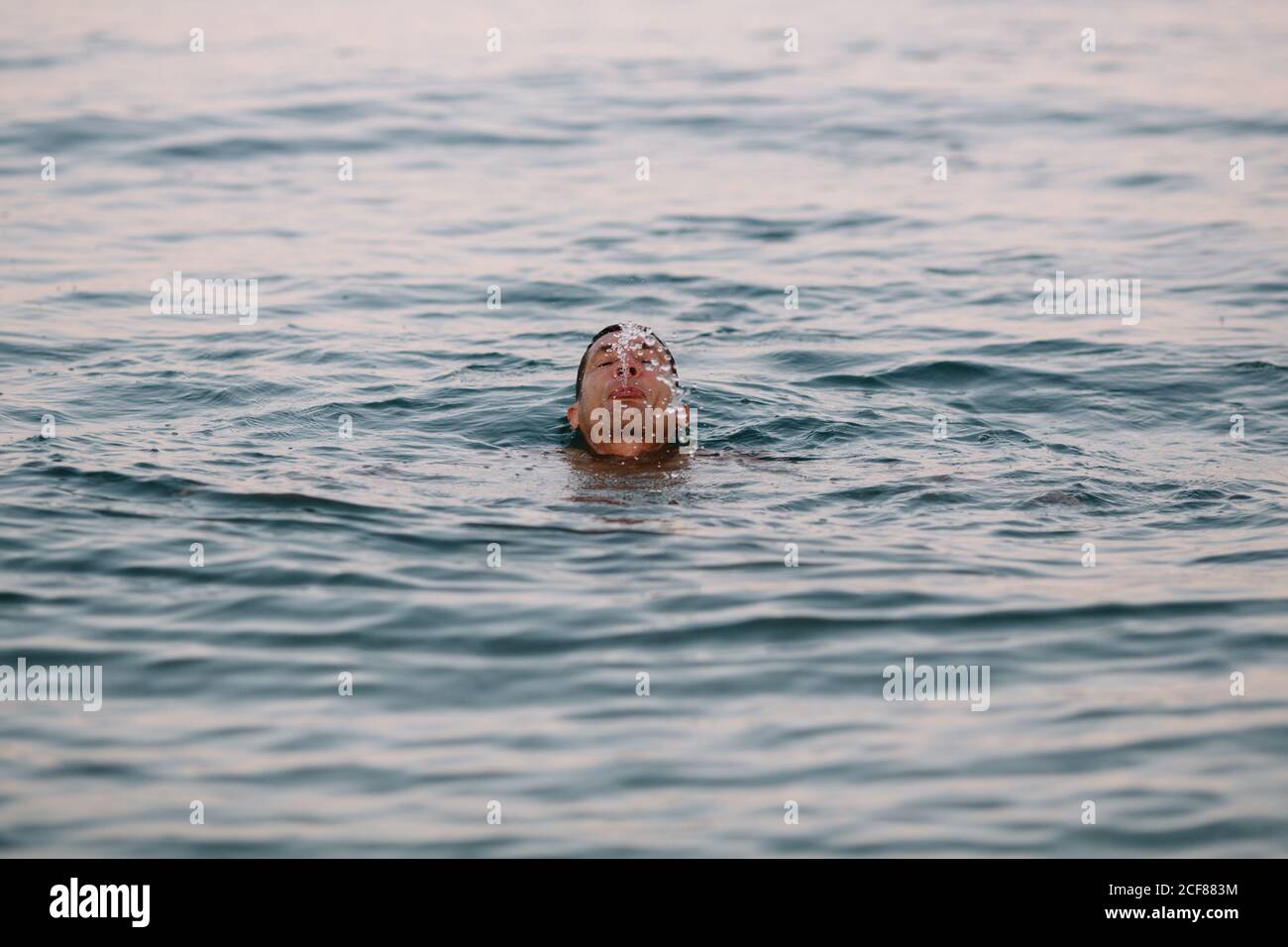 Zufriedener Schwimmer während gesunder aktiver Freizeit in tiefer Ruhe Meer, während Wasser nach dem Tauchen bei sonnigem Tag ausspucken Während der Ferien Stockfoto