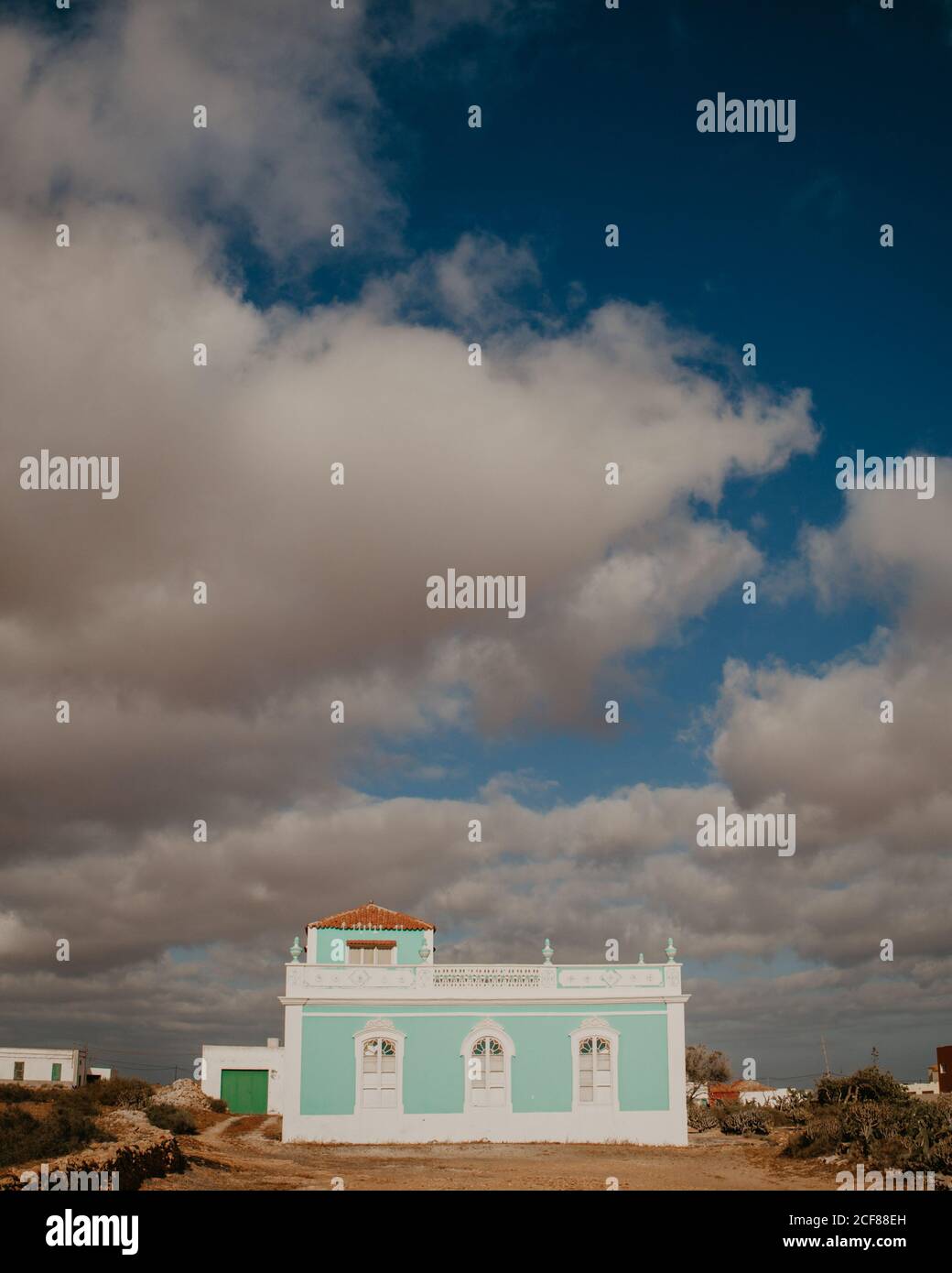 Außenansicht eines kleinen Hauses mit blauer Wand und weißen Elementen auf dem Hof unter blauem Himmel mit Wolken, Kanarische Inseln Stockfoto