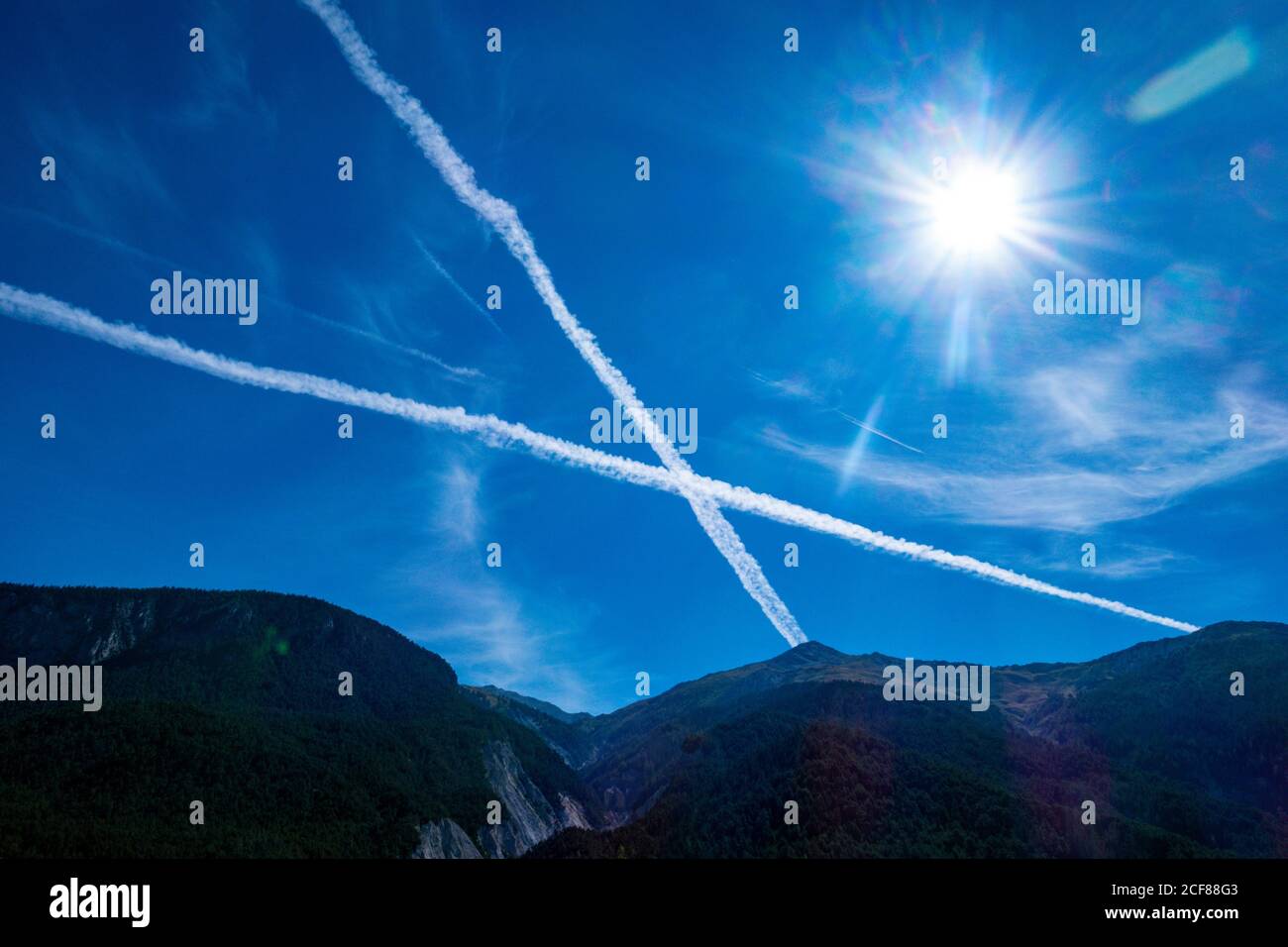 Dampfwege, Contrails in Form eines Kreuzes, in blauem Himmel über den französischen Alpen, Stockfoto
