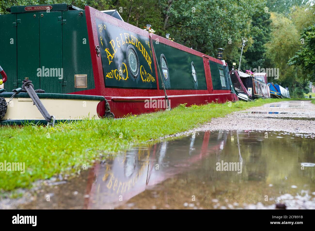 Schöne UK Schmalboot spiegelt sich in großen tiefen Pfütze im Kanal towpath nach schweren Sommerregen. Stockfoto