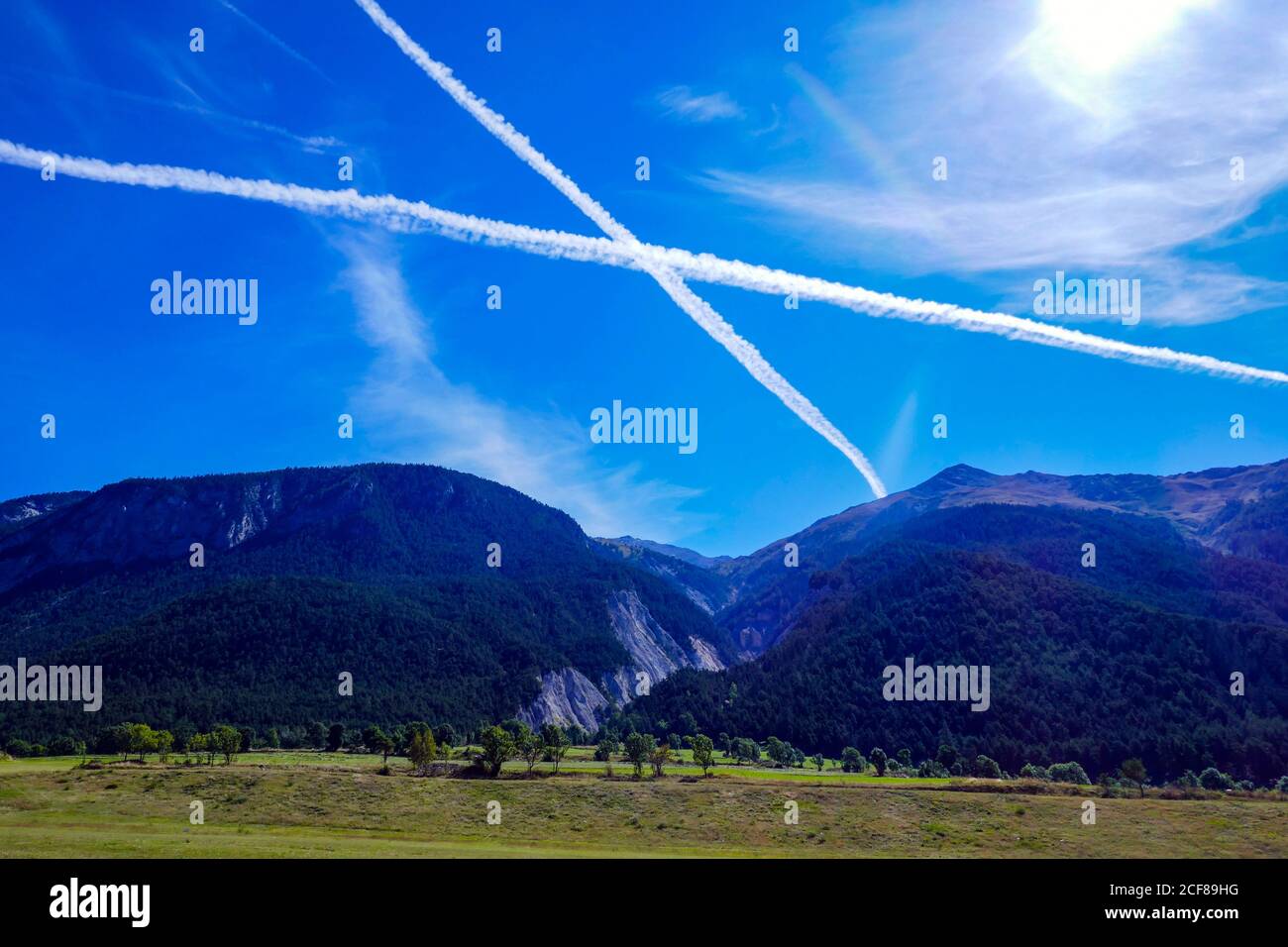 Dampfwege, Contrails in Form eines Kreuzes, in blauem Himmel über den französischen Alpen, Stockfoto