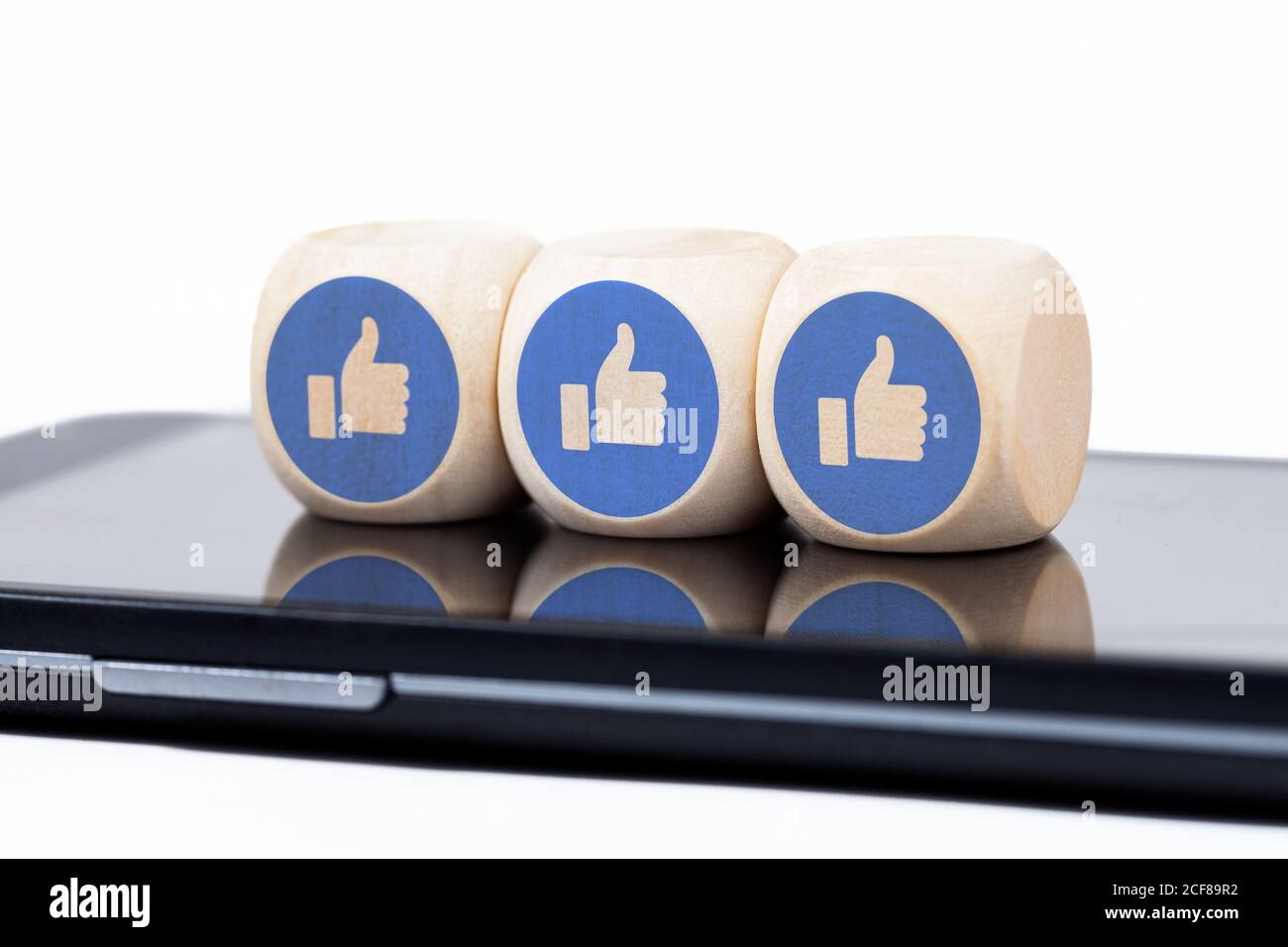 Drei einfache Würfel mit Facebook-ähnlichen Symbolen auf einem modernen Smartphone-Bildschirm. Social-Media-Engagement-Konzept, Angst vor dem Verfehlen, sucht Stockfoto