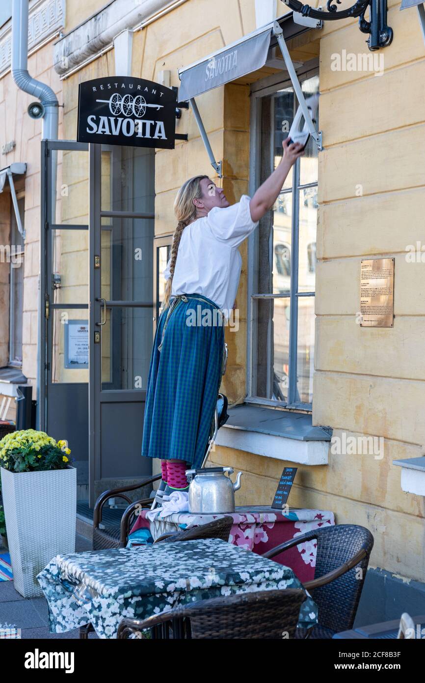 Frau in altmodischen Kleidung Reinigung Restaurant Savotta Fenster in Helsinki, Finnland Stockfoto