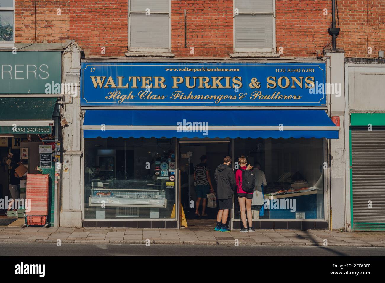 London, Großbritannien - 20. August 2020: Menschen, die sich sozial distanzieren, stehen vor den Fischhändlern von Walter Purkis & Sons in Crouch End, einem Gebiet im Norden Londons Stockfoto
