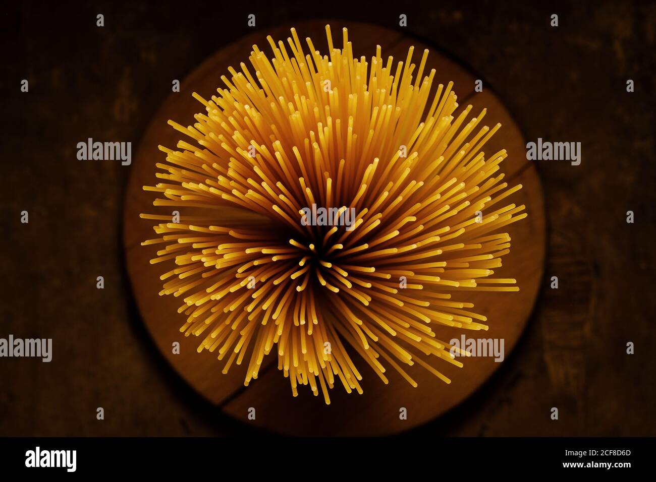 Getrocknete italienische Spaghetti Pasta in einem Behälter Ende auf gesehen Von oben nach unten über einen dunkelbraunen Hintergrund Stockfoto