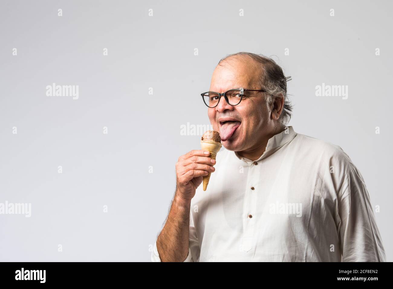 Indischer alter Mann Essen Schokolade Eis in Kegel oder Mango Candy Bar Stockfoto
