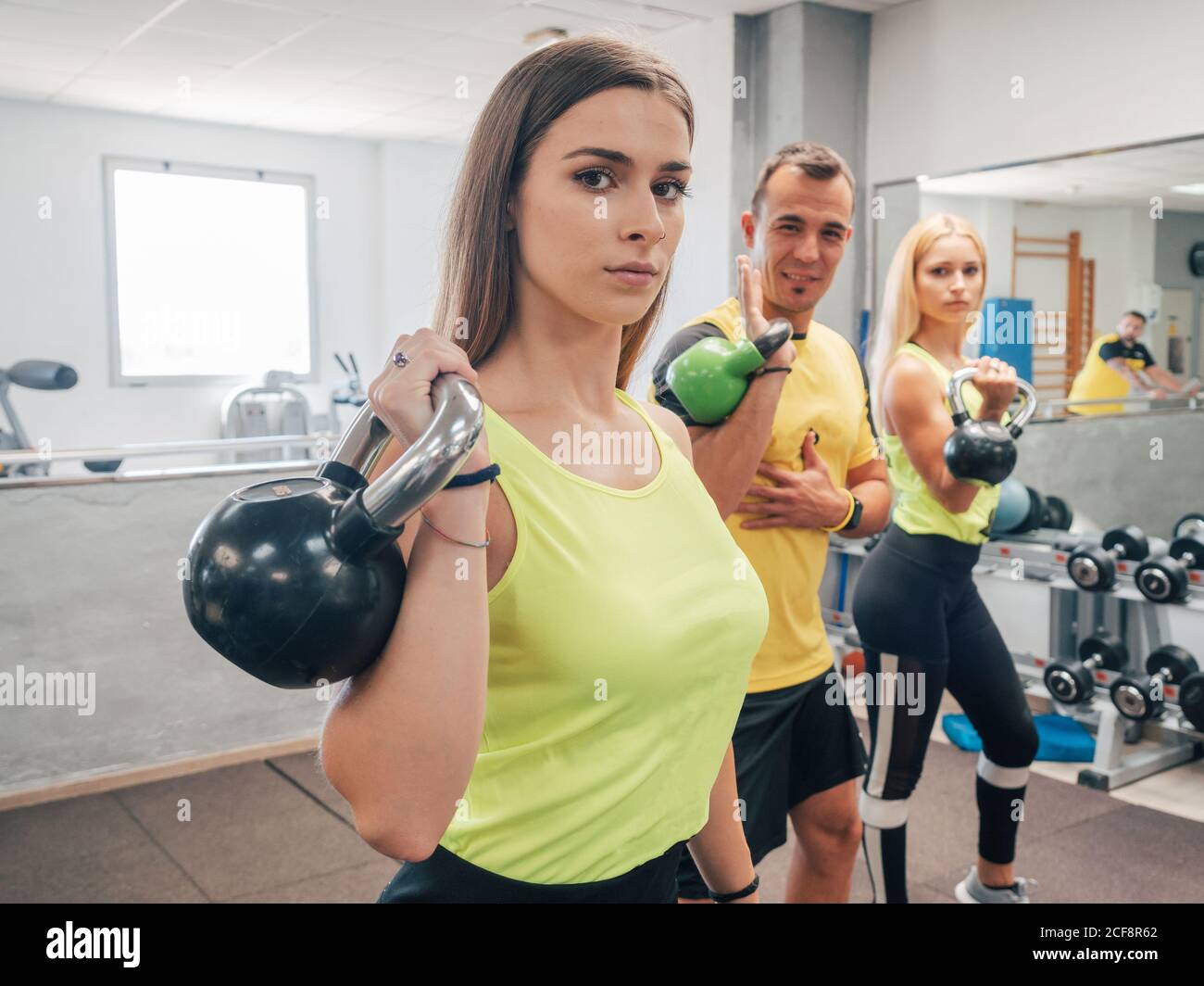 Starke Männer und Frauen beim Heben von Kettlebells während des Trainings im Fitnessstudio Stockfoto