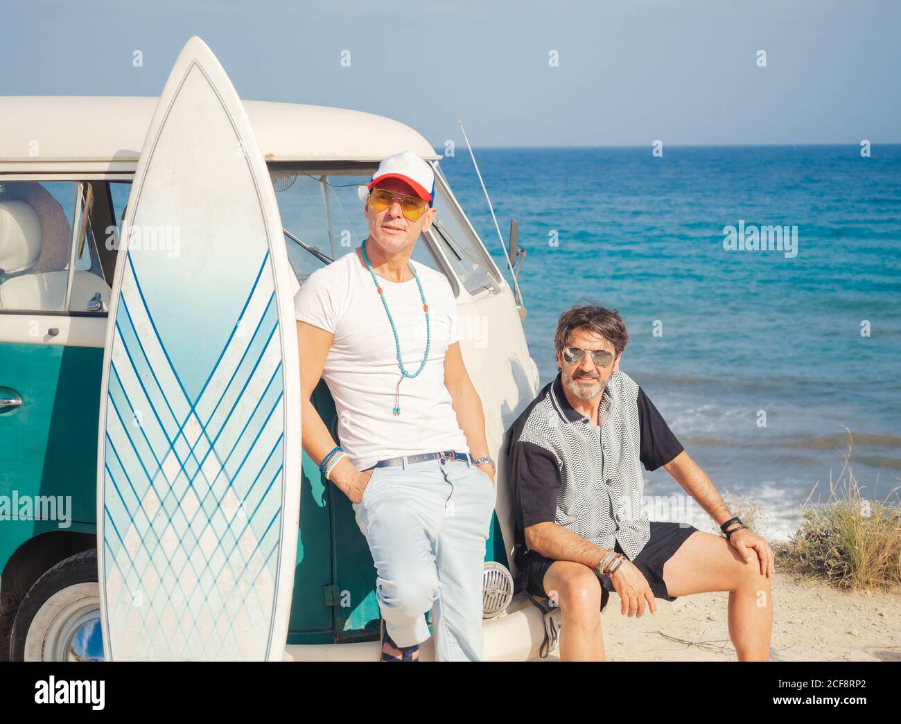 Starke aktive Männer mit großen weißen Surfbrett reden in der Nähe alt Das Auto am Meer blickt weg Stockfoto