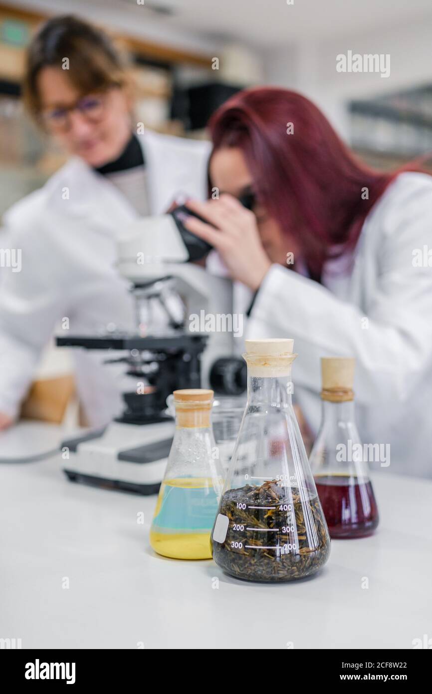 Frau mit Mikroskop in der Nähe von Kollegen im Labor Stockfoto