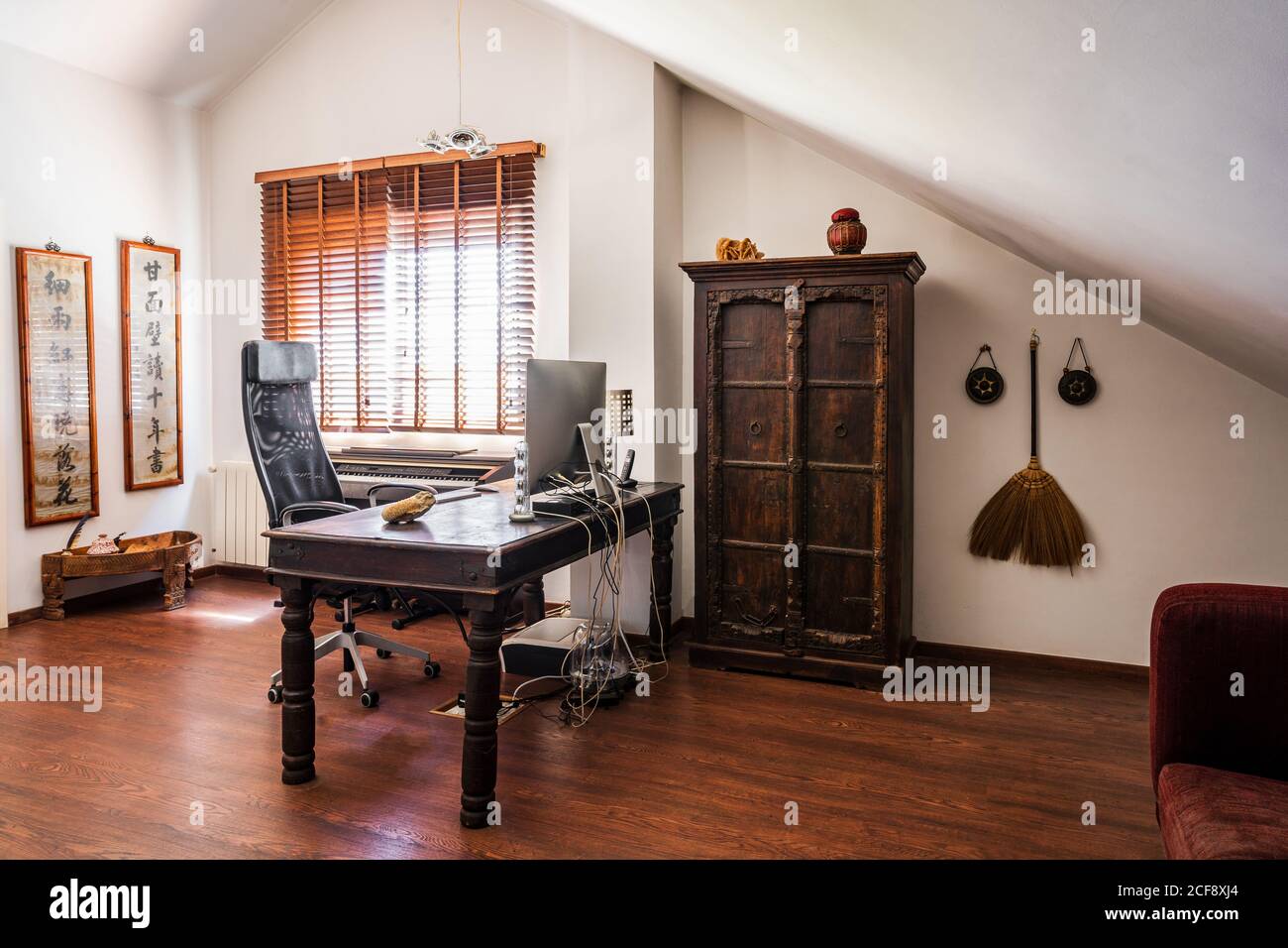 Interior Design des Arbeitsplatzes mit Vintage-Holzmöbel und orientalischen Einrichtung des modernen Apartments mit Holzfußboden und weißen Wänden Stockfoto