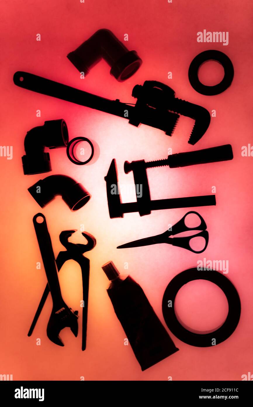 Draufsicht Zusammensetzung von verschiedenen Instrumenten und Materialien für Sanitär Werke auf beleuchtetem rotem Hintergrund angeordnet Stockfoto