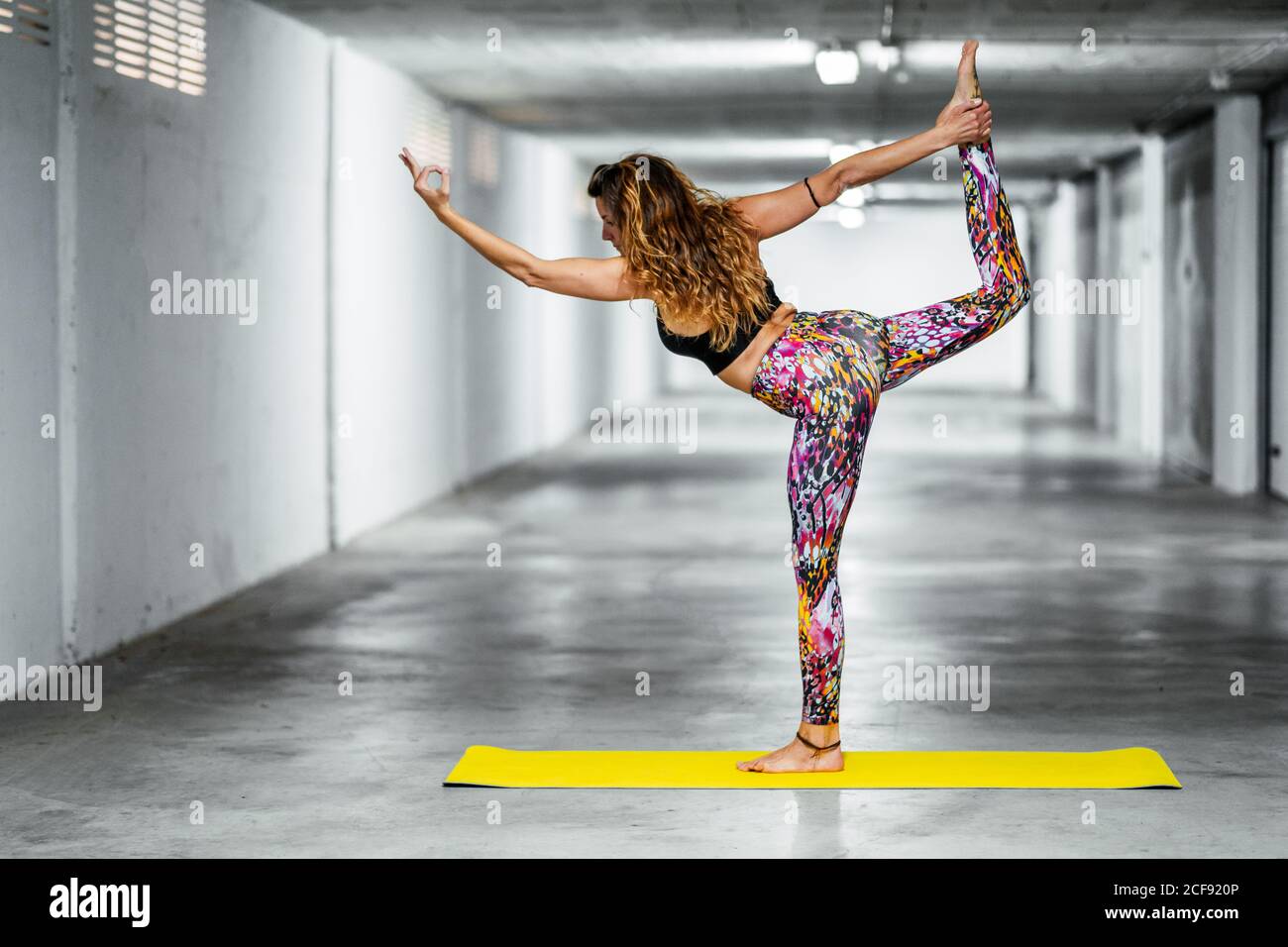 Seitenansicht der Fit junge Frau in Sportswear stehend herr des Tanzes Pose beim Üben Yoga im Licht Garage Halle Stockfoto