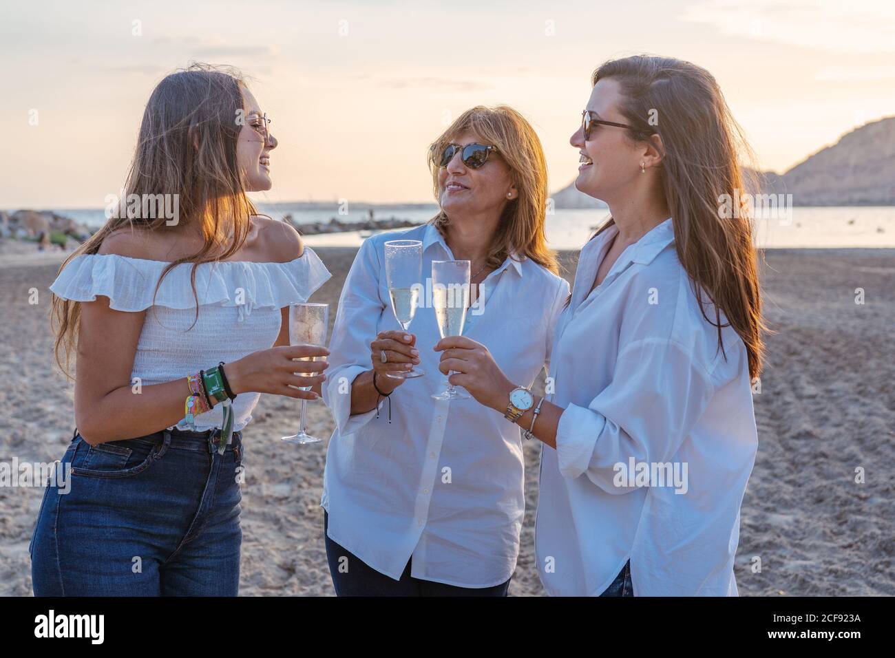 Mutter und junge Töchter klirren Gläser Wein und lachen Wir feierten ein Familientreffen am Abend im Resort Stockfoto