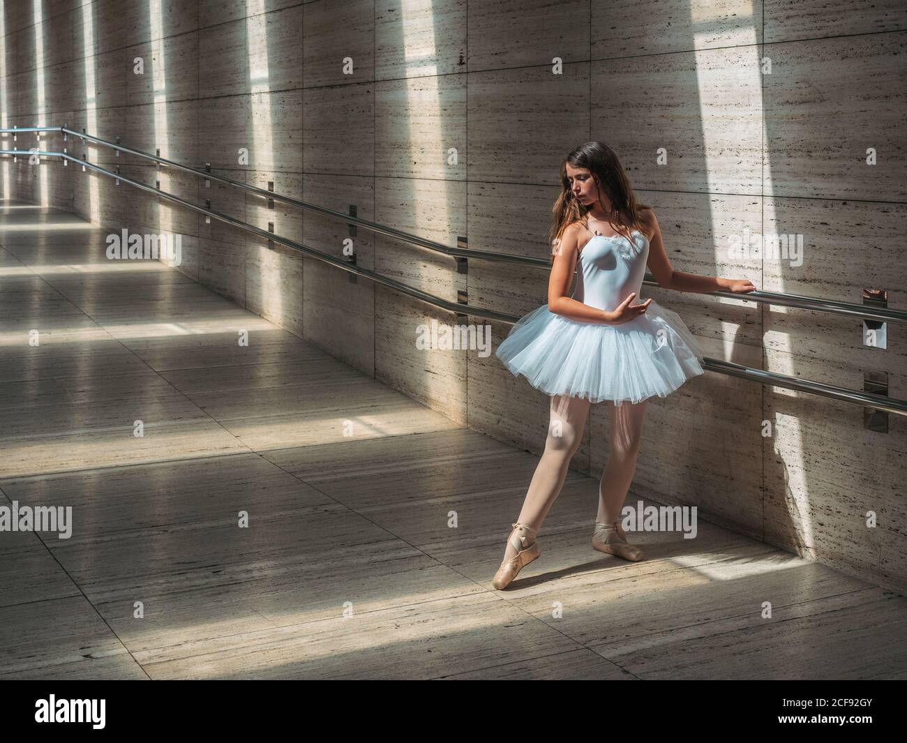 Ballerina in weiß Ballett Tutu Durchführung von Übungen bei Rail in Kontrastreiches Sonnenlicht Stockfoto