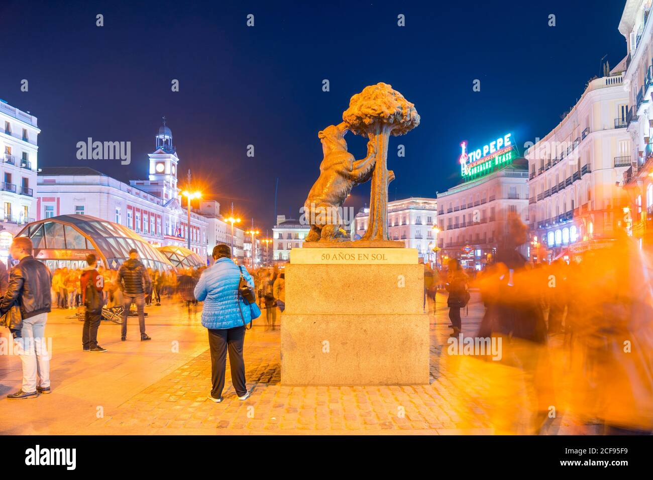Madrid, Spanien - 19. Dezember 2018: Bärenskulptur und Arbutus auf dem Platz Puerta del Sol mit nächtlicher Beleuchtung und Spaziergängen Stockfoto