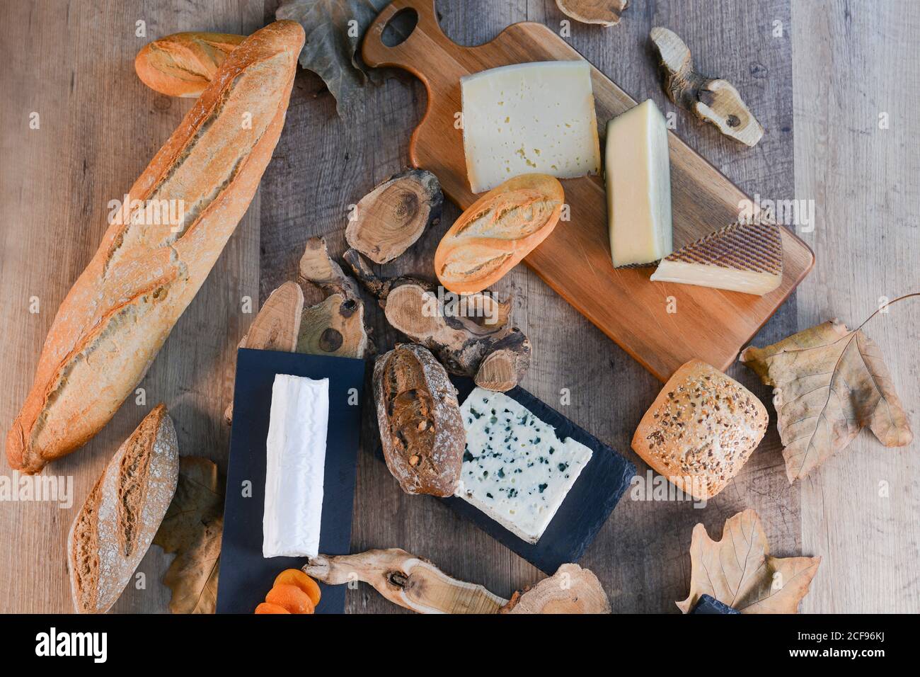 Von oben herrlich verschiedene Arten von Weißkäse und knusprig Frisches Brot mit Holzstücken auf rustikalem Tisch Stockfoto