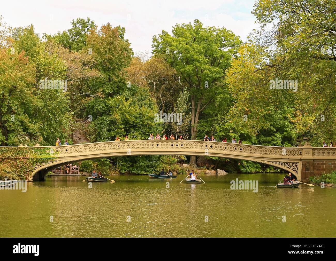 New York City, USA - 7. Oktober 2019: Die Bow Bridge im Central Park. Stöcke über die Brücke gehen oder in den See schauen. Ruderboote sind unter Stockfoto