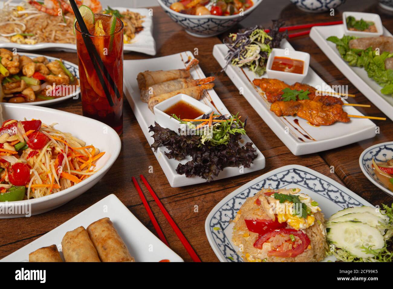 Von oben für verschiedene bunte würzige Thai-Essen serviert Familienessen auf Holztisch mit Essstäbchen Stockfoto