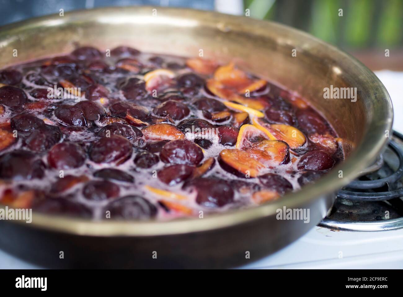 Kochen Pflaumenmarmelade mit Zitrone und Gewürzen in einem Kupfer Waschbecken auf einem Gasherd Stockfoto