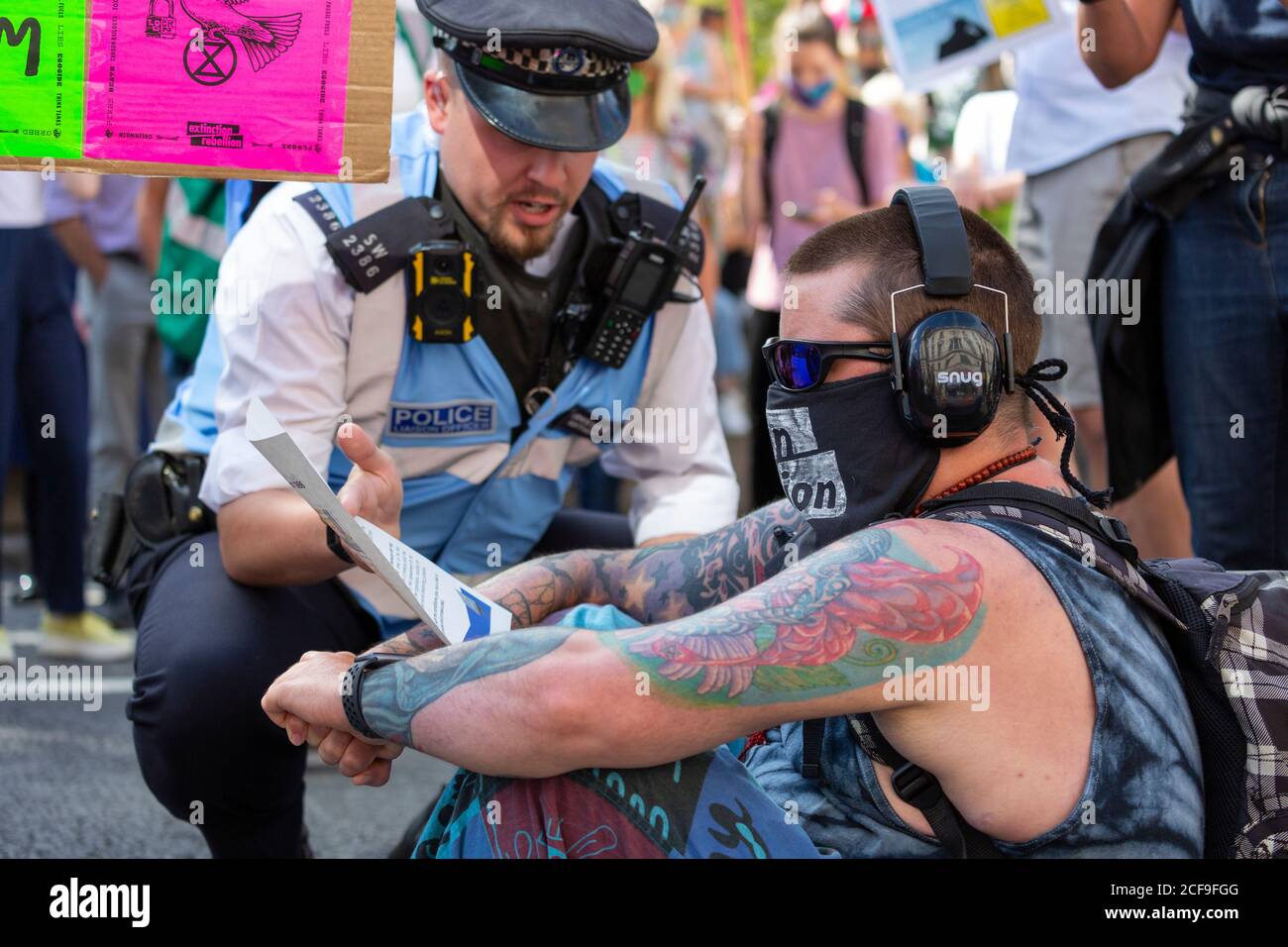 Ein Polizeibeamter spricht mit einem Protestierenden, der die Straße blockiert, Demonstration des Extinction Rebellion, Parliament Square, London, 2. September 2020 Stockfoto